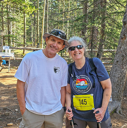 Man and a woman standing together in the forest at Barr Camp.