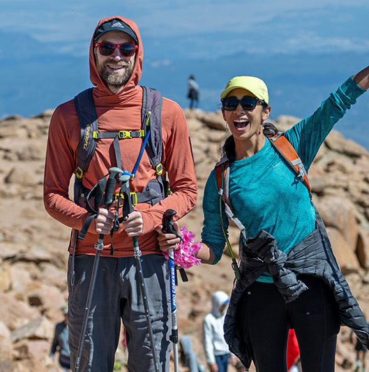 Man and woman hikers wearing hiking gear, at the summit of Pikes Peak.